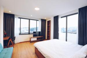 TTR Studio Apart Hotel في دالات: غرفة نوم بسرير ومكتب مع تلفزيون