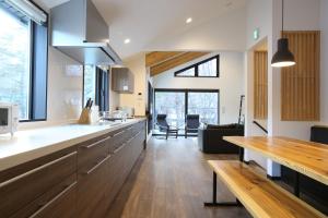 a kitchen with a long counter and a living room at Snowlines Apartments Hakuba in Hakuba