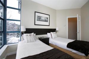 two beds in a room with a window at Alpenglow Lodge by Bill in Whistler