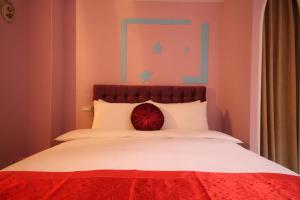 Una cama con una almohada roja encima. en Moroccan Holiday Suite, en Hualien City