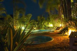 a swimming pool in a garden at night at Pousada Além do Jardim in Praia do Rosa