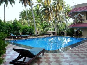 a swimming pool with a table and chairs next to a house at Ganesh Ayurveda Holiday Home Apartment in Kovalam