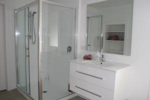 a white bathroom with a shower and a sink at Bridgehaven Guesthouse in Okoroire