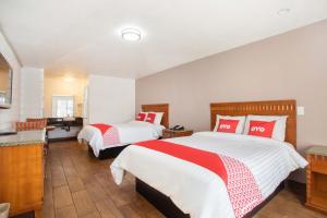 a bedroom with two beds with red and white pillows at OYO Hotel Palmdale - Antelope Valley in Palmdale