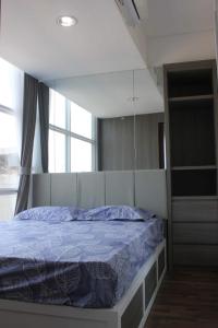 a bedroom with a bed in a room with a window at Apartemen Grand sungkono Lagoon Venetian. in Surabaya