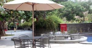 einen Tisch und Stühle mit einem Sonnenschirm neben einem Pool in der Unterkunft Apartemen Grand sungkono Lagoon Venetian. in Surabaya