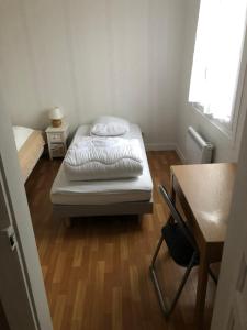 ein kleines Schlafzimmer mit einem Bett, einem Schreibtisch und einem Stuhl in der Unterkunft Chez Nono et Soso in Eurville