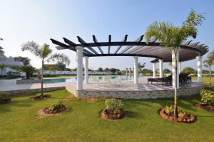 a pavilion with tables and palm trees and a pool at Umaid Farm Resort- A Legancy Vintage Stay In Jaipur in Jaipur