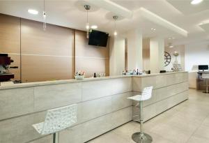 a lobby with a bar with two chairs and a tv at Hotel Rubens in Rimini