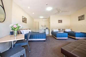 a room with three beds and a table and chairs at Matilda Motor Inn in Dubbo