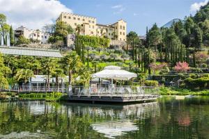 a boat in a lake with a building in the background at Relax Suite in Merano