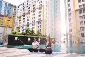 dos mujeres sentadas en una pose de yoga frente a una piscina en Vega Hotel Gading Serpong, en Serpong