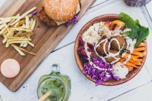 a table with a plate of food and a hamburger and fries at Green Hill Mirissa in Mirissa