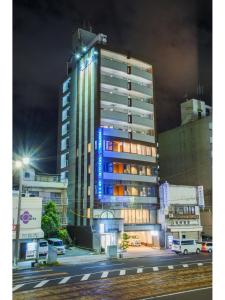 un edificio alto con luces azules en el costado en Sejour Inn Capsule en Hiroshima
