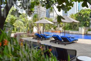a group of chairs and umbrellas next to a pool at The Residences of The Ritz-Carlton Jakarta Pacific Place in Jakarta