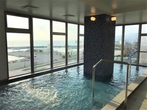een groot zwembad in een gebouw met ramen bij Green Rich Hotel Okinawa Nago (Artificial hot spring Futamata Yunohana) in Nago