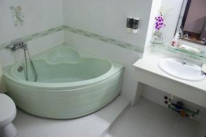 a bathroom with a green bath tub next to a sink at Hoa Phat Hotel & Apartment in Ho Chi Minh City