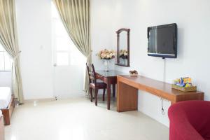 Zimmer mit einem Schreibtisch und einem TV an der Wand in der Unterkunft Hoa Phat Hotel & Apartment in Ho-Chi-Minh-Stadt