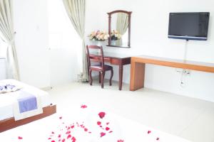 a bedroom with a desk and a table with flowers on the floor at Hoa Phat Hotel & Apartment in Ho Chi Minh City