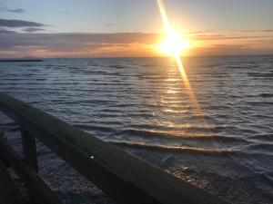 a sunset over the water with a wooden fence at Donna's Bed & Breakfast in White Rock