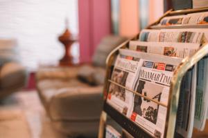 eine Reihe von Zeitungen auf einem Tisch mit einer Couch in der Unterkunft Ritz Grand Hotel Mandalay in Mandalay