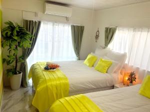 沖縄市にある海の見える高台にあるテラス付きハウス!! 家族旅行に最適!!のベッドルーム1室(黄色いシーツを使用したベッド2台付)
