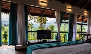 a bedroom with a bed and a large window at Pranavam Resort & Spa in Tariyod
