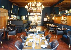 een restaurant met tafels en stoelen en een kroonluchter bij Hotel Detmolder Hof in Detmold