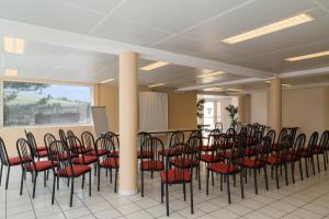 une rangée de chaises et de tables dans une pièce dans l'établissement The Originals City, Hôtel L'Acropole, Saint-Etienne Sud (Inter-Hotel), à La Ricamarie