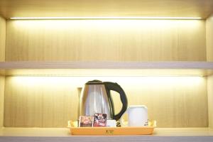 - Hervidor de té y tazas en un estante en Apatel Roseville SOHO & Suite, en Tangerang