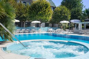 a large swimming pool with chairs and umbrellas at Hotel Paris Resort in Bellaria-Igea Marina