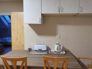 a kitchen with a table with a toaster and two chairs at Bella Apartman in Szeged