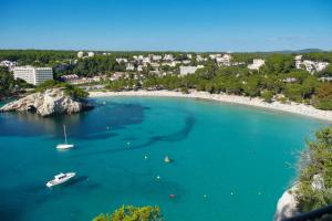 a view of a beach with a boat in the water at Minura Cala Galdana & Apartamentos d'Aljandar in Cala Galdana