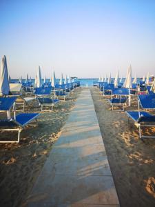 uma fila de espreguiçadeiras azuis numa praia em Il Battello em Cesenatico