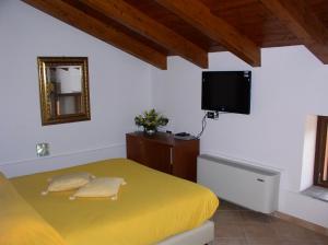 a bedroom with a yellow bed and a flat screen tv at Country House Casale D'Orio in Ascea