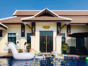 a group of children playing in the water in front of a house at Lanna Kamin Pool Villa Airport in Chiang Mai