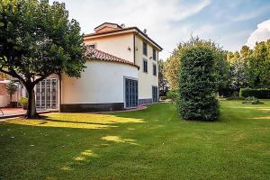 una casa con un patio verde con un árbol en Villa Apostolico with private pool, en Éboli