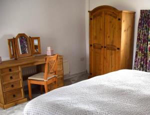 a bedroom with a wooden dresser and a bed and a desk at Tuck Mill Cottage in Castlewellan