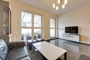 a living room with a couch and a tv and a table at Downtown Apartments Hallera 165 in Gdańsk