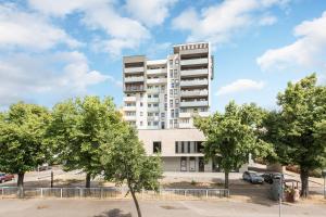 a tall white building with trees in front of it at Downtown Apartments Hallera 165 in Gdańsk