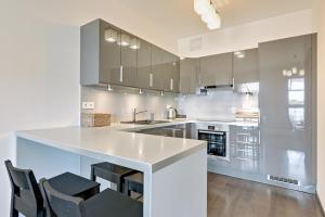 a kitchen with a white counter and chairs in it at Downtown Apartments Hallera 165 in Gdańsk