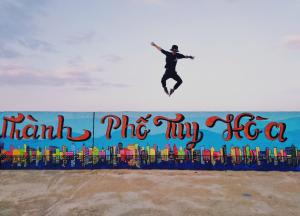 Ein Mann springt über eine Mauer in die Luft in der Unterkunft Yellow Farm homestay in Ðông Tác (1)