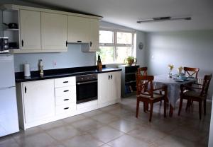 eine Küche mit weißen Schränken und einem Tisch mit Stühlen in der Unterkunft Tuck Mill Cottage in Castlewellan + 13 Fotos