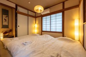 a large white bed in a room with a window at Tsukiyume Kan - Entire Private House, Free Parking, 10min USJ & Tennoji, Airport Direct Train, Family Group Sleeps 8, 和モダン貸切一軒家 ユニバーサルスタジオ in Osaka