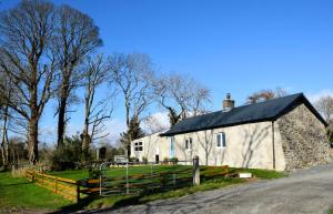 a white barn with a black roof on a road at Tuck Mill Cottage in Castlewellan