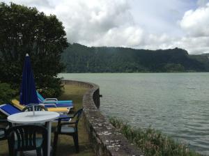 a group of chairs and tables next to a lake at Casa Dos Barcos Furnas in Furnas