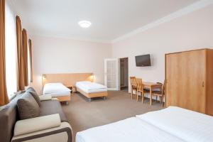 ein Hotelzimmer mit einem Sofa, einem Bett und einem Tisch in der Unterkunft Hotel v Centru in Budweis