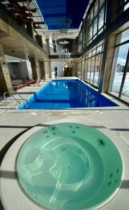 a large swimming pool with a green tub in a building at Atrium New Gudauri by Gudauri Travel in Gudauri