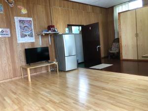 een woonkamer met een televisie en een koelkast bij 東のオズ in Higashi