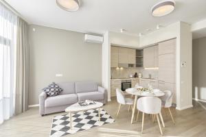ein Wohnzimmer mit einem Sofa, einem Tisch und Stühlen in der Unterkunft Asian Magnolia Boutique Apartments in Druskininkai
